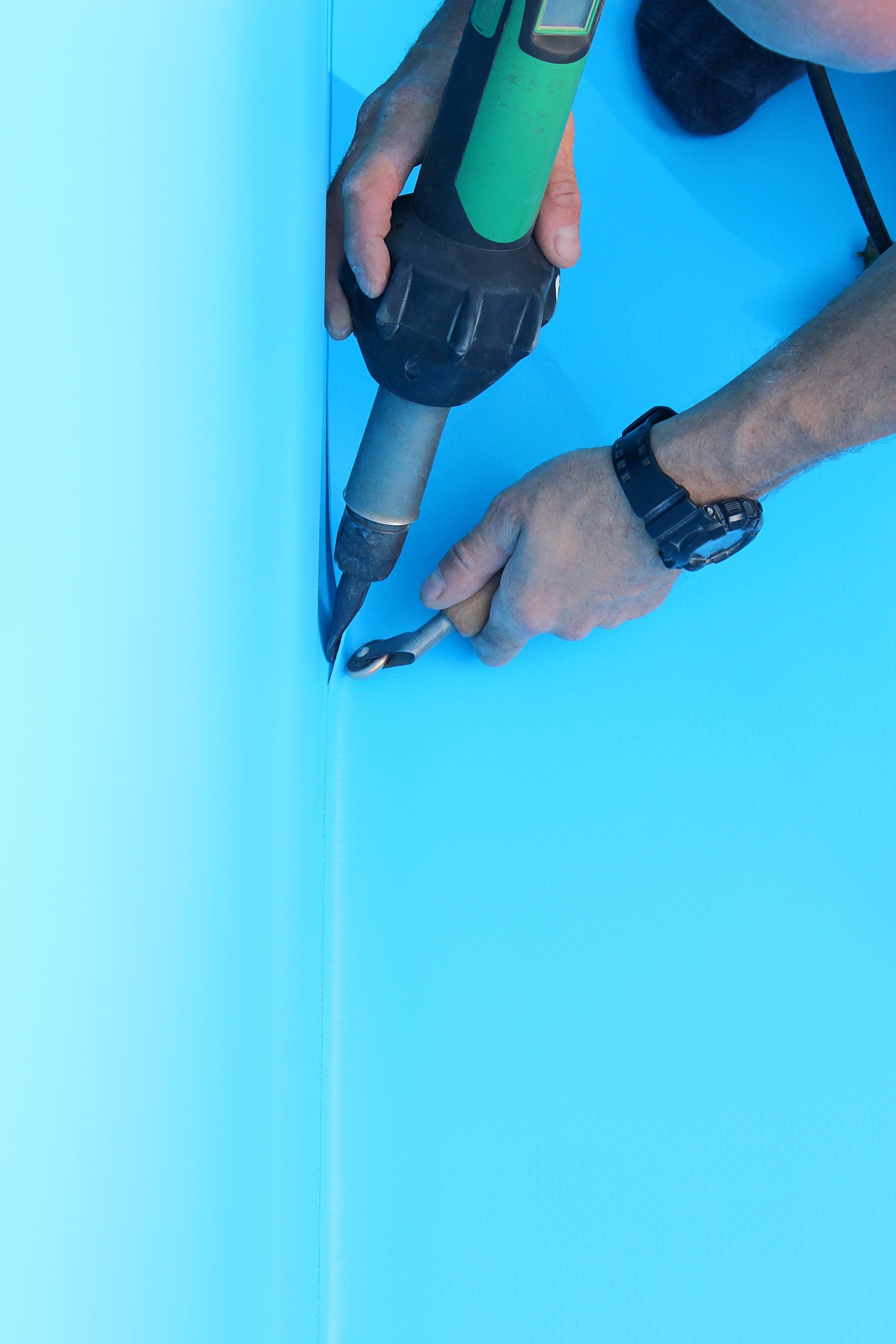 Installing a swimming pool liner with tools.