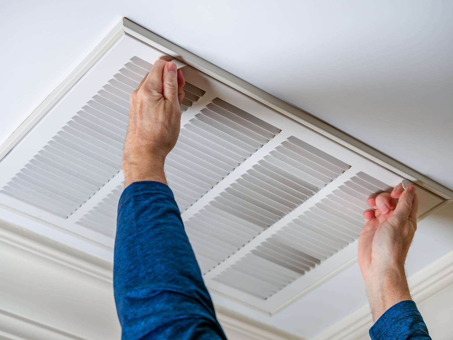Person replacing air filter in ceiling vent