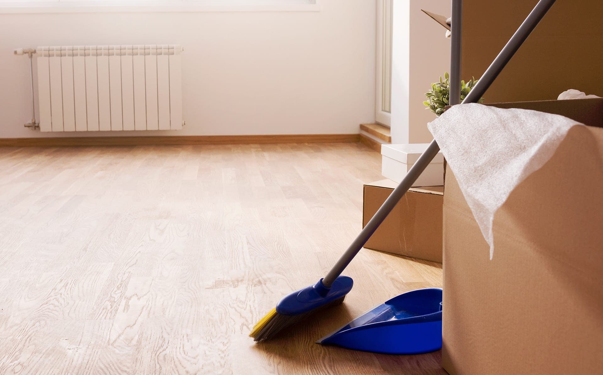 Broom, dustpan, and boxes on wooden floor