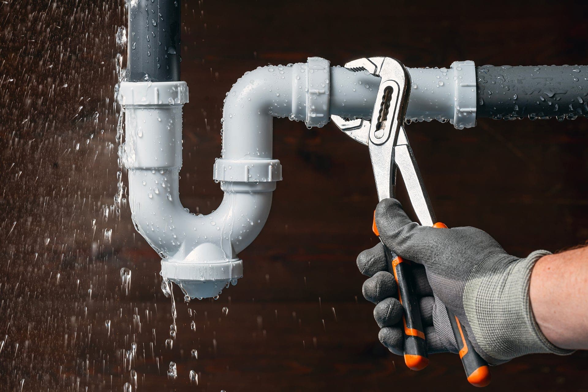 NexLvl plumber repairing a leaking pipe with a wrench