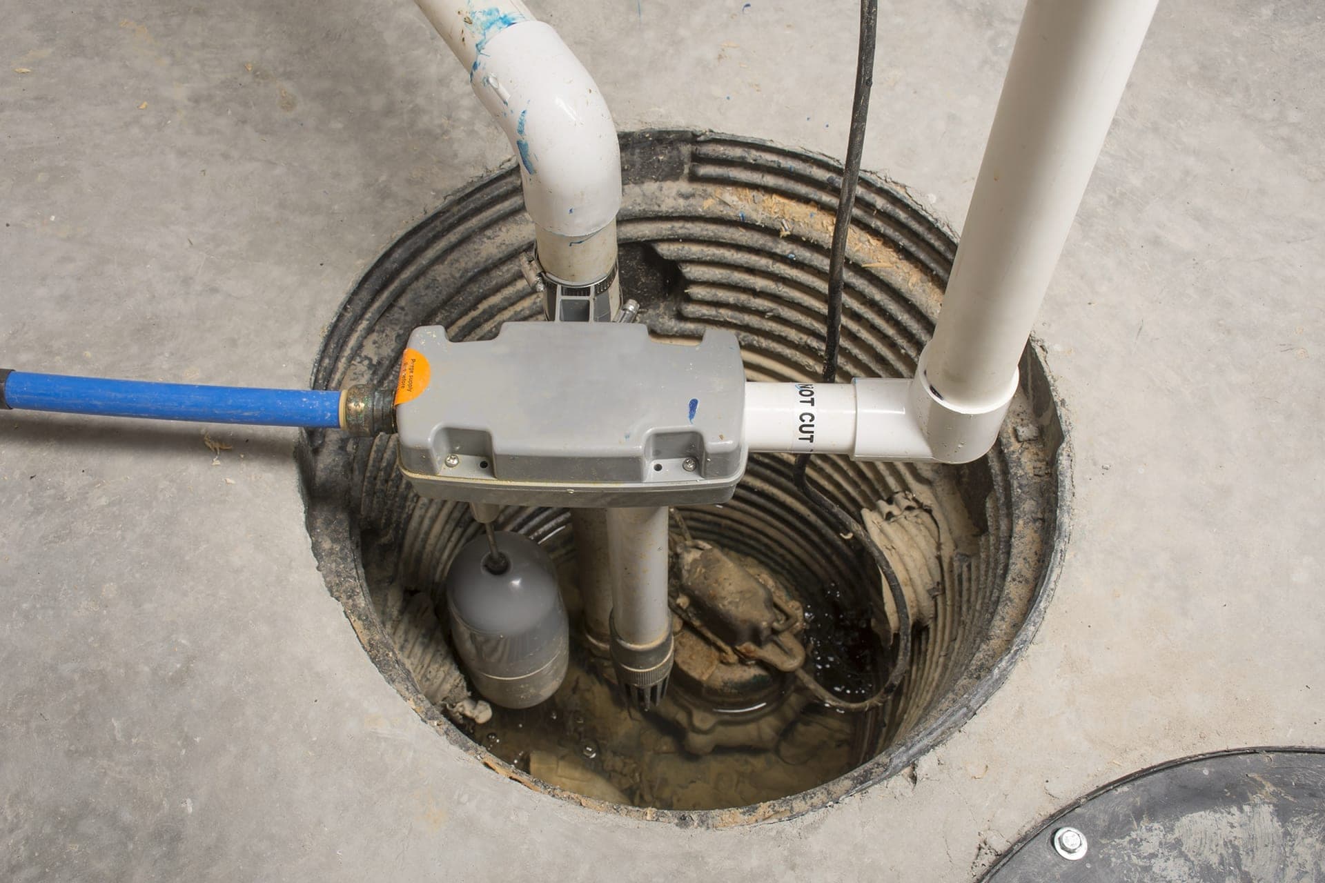 Sump pump system in a concrete basement pit.